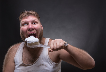 Adult man cleaning teeth over darck backgroundの写真素材