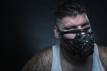 Adult agressive man in muzzle in the dark