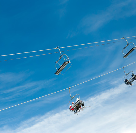 Skiers on ski lift against blue skyの写真素材