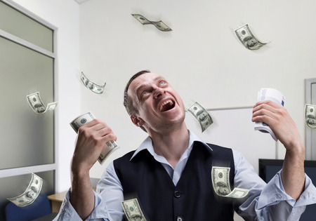 Happy businessman holds money and dreams in the officeの写真素材