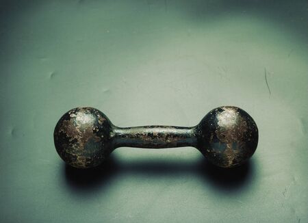Old steel dumbbell weight on dark background. Toned imageの写真素材