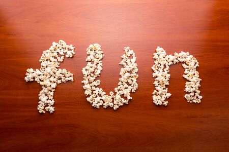 Popcorn forming the word \"fun\" on the wooden tableの写真素材
