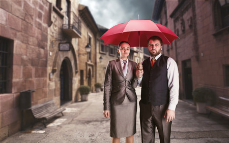 Business couple under umbrella against ancient streetの写真素材