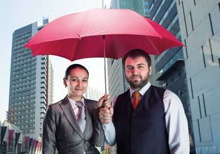 Business couple under umbrella against the cityの写真素材
