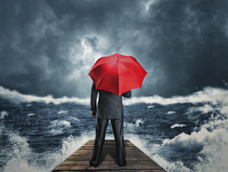 Man with red umbrella standing back on the pier at night stormの写真素材