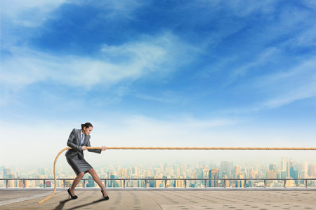 Businesswoman pulls something against blue skyの写真素材