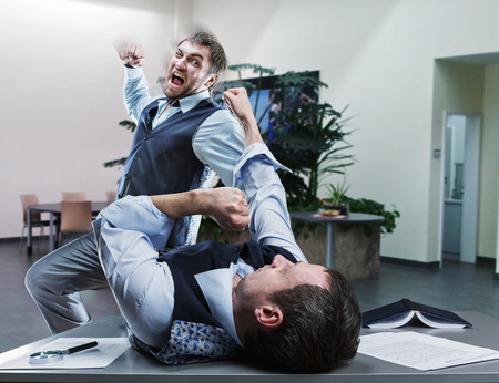 Two furious businessmen fighting in the officeの写真素材
