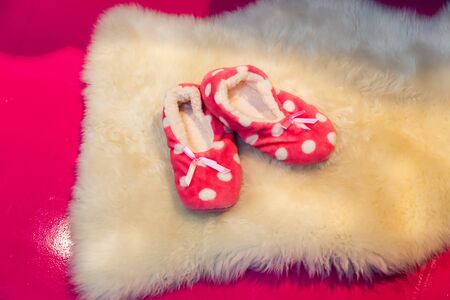 Cute rose childs slippers on a fur carpetの写真素材