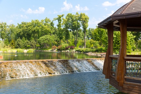 Beautiful lake in green park with wooden summer-houseの写真素材