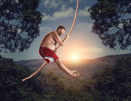 Happy savage flying in the air by rope in the forest at nightの写真素材