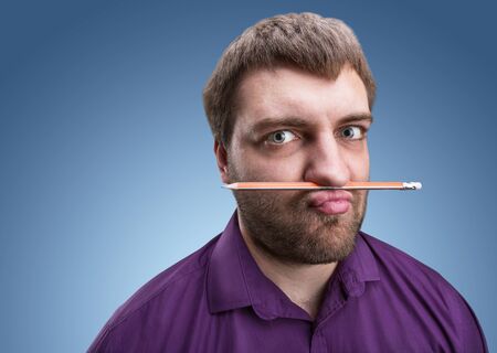 Strange bearded man holds pencil with his nose and lipsの写真素材