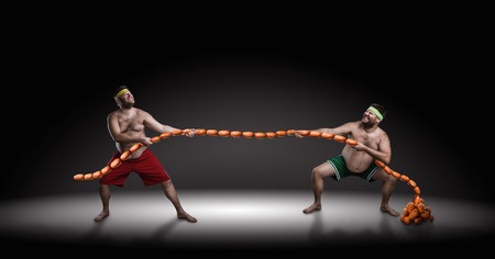 Two men fighting for sausages over black backgroundの写真素材