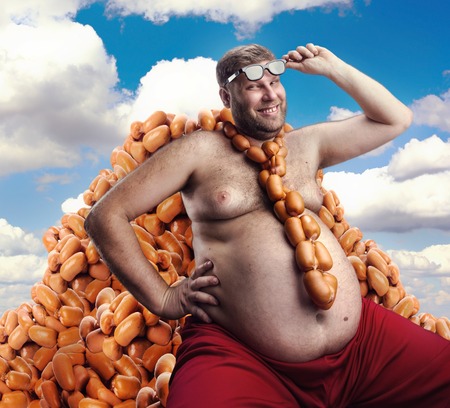 Smiling man sitting on the heap of sausages and with sausages round his neckの写真素材