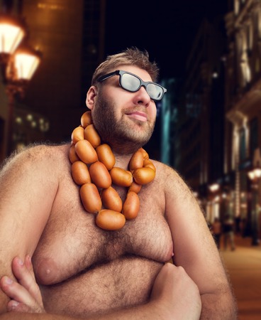 Cool man in glasses with sausages on his neck sits in the evening cityの写真素材