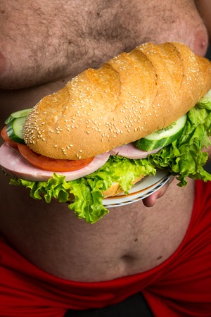 Fat happy man in glasses with sandwichの写真素材