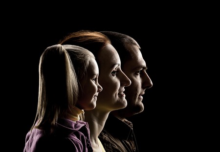 Profile view of little daughter, mother and father over black の写真素材