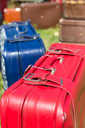 Red and blue old suitcases stand on the grass