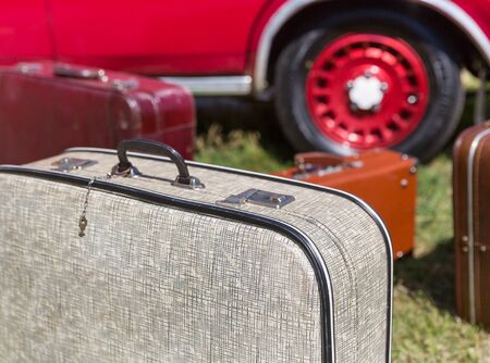 Old suitcases standing on the grass near a retro carの写真素材