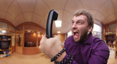 Angry businessman man screaming into the phoneの写真素材