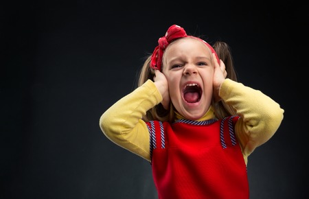Little girl is screaming with her ears covered by handsの写真素材