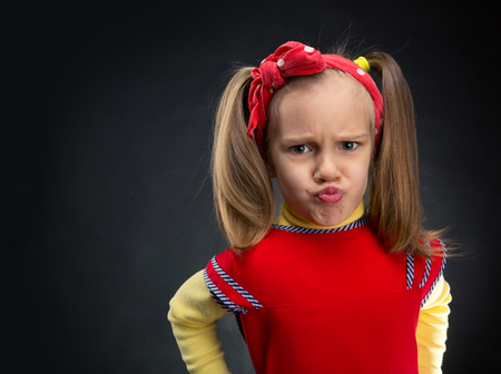 Funny little girl making faces over grey backgroundの写真素材