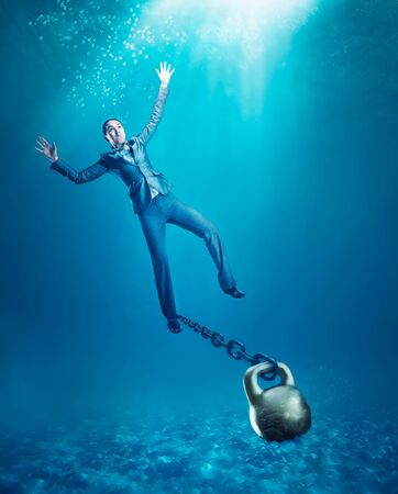 Businesswoman with dumb-bell on her hand sinking in the seaの写真素材