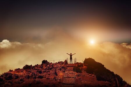 Woman standing back on the mountain peak at sunset, Portugal, Madeiraの写真素材