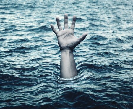 Hand of drowning man in sea asking for helpの写真素材