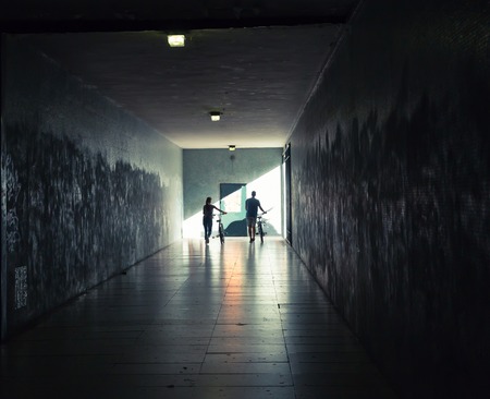 Young woman and man with bicycles in the tunnel undergroundの写真素材