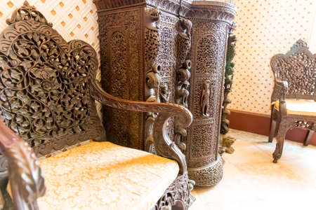 Luxurious wooden armchairs and cabinet with carved patternの写真素材