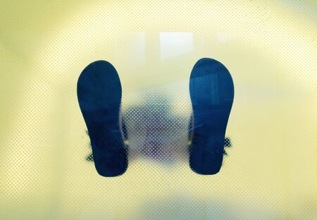 Bottom view through the glass of man's shoes feetの写真素材