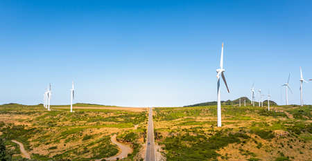 Road in the valley with big windmills on each sideの写真素材