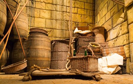 Old lit lumber-room with wooden baskets, barrels and ropesの写真素材