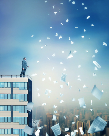 Businessman looking at falling documentsの写真素材