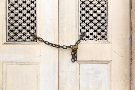 Old wooden faded door locked with chainの写真素材