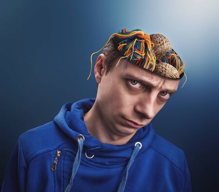 Young man with balls of yarns instead of his brain