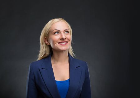 Smiling businesswoman dreams over grey background