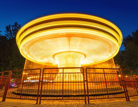 Fast merry-go-round lighting in the night parkの写真素材
