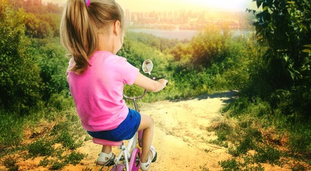 Cute little girl cycling on pink bike in the forestの写真素材