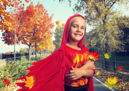 Little girl in masquerade costume in an autumn streetの写真素材