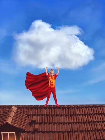 Little girl in costume holding a big cloud standing on the roofの写真素材