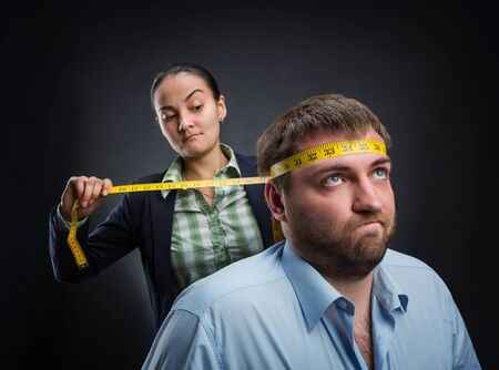 Businesswoman measuring man's head with metre-stickの写真素材