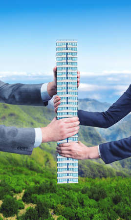 Businesspeople holding in their hands big office buildingの写真素材