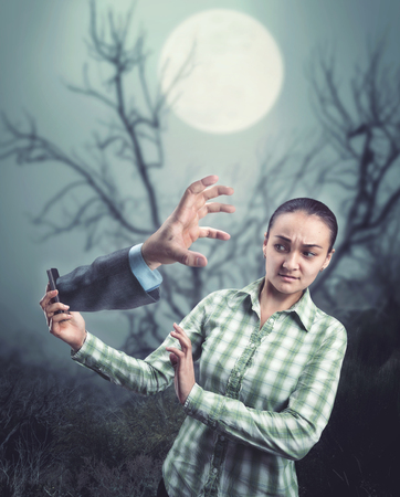 Businesswoman hand with a phone with man's hand from it in the forest at nightの写真素材