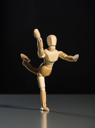 Human wood manikin dancing against dark backgroundの写真素材