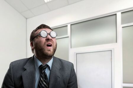 Surprised nerd businessman in glasses at officeの写真素材
