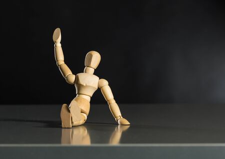 Human wood manikin sitting on the floor against dark background