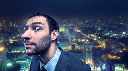 Curious businessman over evening ciry backgroundの写真素材