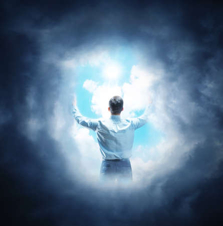 The man pushes the clouds to the sides with sun in the centerの写真素材