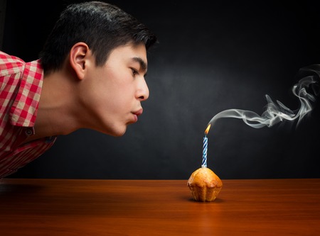 Birthday boy blowing out one candle in a little cakeの写真素材